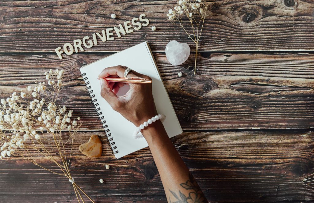 Hand writing a forgiveness list on a wooden table